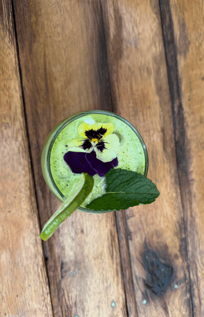 Refreshing mint lemonade garnished with lime, fresh mint, and an edible flower — a vibrant green drink infused with huacatay, served at Green Point Vegan Restaurant in Cusco, Peru.