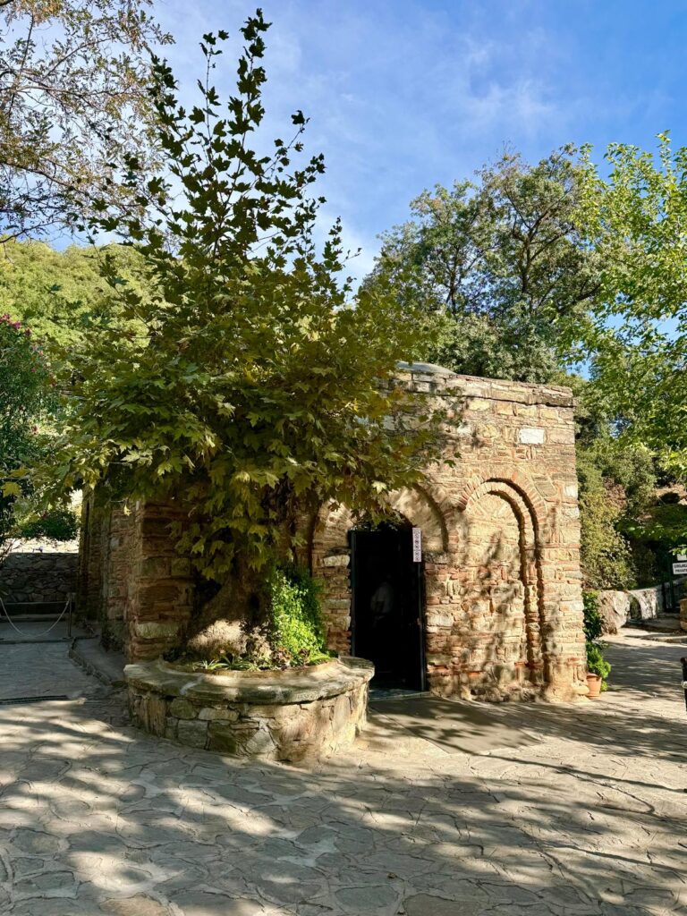 Starseed Türkiye Adventure 2026, exterior view of Mary's House near Ephesus surrounded by trees, stone pathways, and a historic devotional landscape.